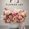 Pink and white rose arrangement in a white bowl vase with a ribbon