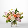 Pink and peach roses in a clear glass vase with small purple flowers