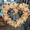 Heart-shaped floral wreath with white roses and pale pink blooms on an easel