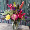Mixed bouquet with pink lilies, yellow carnations, and purple flowers in a glass vase