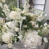 White floral arrangement with roses, hydrangeas, and snapdragons in a basket