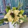 Cream floral arrangement in a white vase with long greenery accents