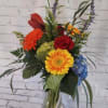 Mixed bouquet in a clear glass vase with red, yellow, orange, and blue flowers