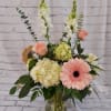 Pink gerbera and roses with white blooms in a glass vase