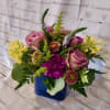 Mixed bouquet of pink roses and purple flowers in a blue vase