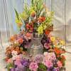 Large colorful floral arrangement around a silver vase
