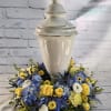 Blue and yellow floral arrangement around a white urn