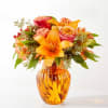 Orange and pink mixed bouquet in an amber glass vase