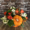 An orange ceramic pumpkin with lid filled with festive fall colors. 