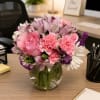 Clear glass bowl with a bouquet filled with carnations, alstroemeria, statice, daisies.