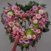 Heart-shaped floral wreath with pink and white flowers and a pink ribbon