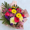 Mixed bouquet of roses, gerbera daisies, and chrysanthemums wrapped in pink paper