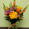 Mixed bouquet in a glass vase with yellow, orange, and purple flowers
