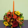 Autumn floral centerpiece with roses, sunflowers, and a tall orange candle