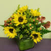 Sunflower arrangement in a green glass vase with berries and greenery