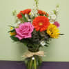 Mixed bouquet of pink, orange, and yellow flowers in a glass vase