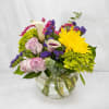 Mixed bouquet of roses, calla lilies, and chrysanthemums in a glass bowl vase