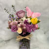 Purple and pink mixed bouquet in a glass vase with a pink butterfly pick