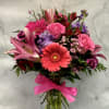 Pink and purple mixed bouquet in a glass vase with a bright ribbon
