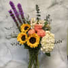 Bouquet of sunflowers, roses, and hydrangea in a glass vase