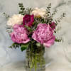 Ruffled pink peonies take center stage in this garden-style flower arrangement, a