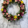 A richly layered, circular sympathy wreath designed to convey warmth and remembrance-this