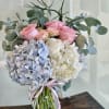 Pink roses and blue-white hydrangeas in a glass vase with ribbon