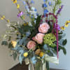 Tall mixed bouquet in a glass vase with pink roses and blue flowers