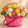Colorful roses and carnations in a pink basket with pastel eggs
