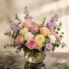 Bouquet of pink and peach roses with lavender flowers in a glass vase