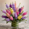 Colorful mixed bouquet in a glass vase with tall purple, pink, white, and yellow blooms