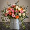 Pink, white, and orange roses in a metal watering can