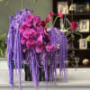 Purple and pink orchid arrangement in a black vase