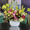 Mixed pink and green floral arrangement in a white textured vase