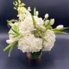 White floral arrangement with tulips and hydrangeas in a woven basket