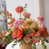 Peach and pink mixed bouquet in a tan vase