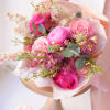 Pink rose and ranunculus bouquet wrapped in pale paper