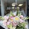 A lush, garden-style bouquet featuring soft pink peonies, garden roses, snapdragons, and