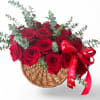 Red roses in a wicker basket with eucalyptus and a red ribbon