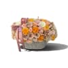 Low arrangement of pastel roses in a textured silver container with a pink ribbon