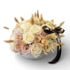 Cream and blush roses in a white textured bowl with a dark ribbon