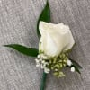 White rose boutonniere with small white filler flowers and green leaves