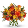 Autumn bouquet of orange roses and mixed flowers in a clear glass vase