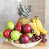 Basket of assorted fruit with pineapple, bananas, grapes, apples, and kiwi