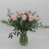Pink roses in a clear glass vase with airy greenery
