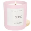 Pink scented candle in a glass jar with a lit wick