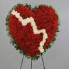 Heart-shaped red floral wreath with white roses on a stand