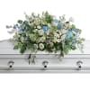 White and blue floral casket spray with greenery