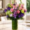 Mixed pink and purple flower arrangement in a tall glass vase