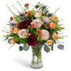 Mixed bouquet of roses, chrysanthemums, and thistle in a clear glass vase